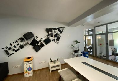Bright conference room with a large white meeting table and wall art made of hardware components.