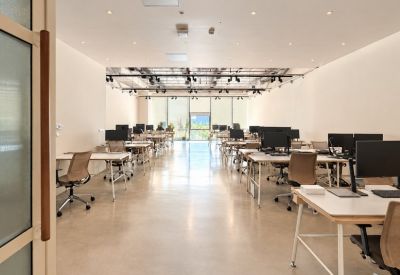 Bright open-plan workspace with multiple ergonomic desks and neutral tones.
