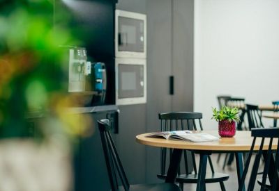 Kitchenette area with a coffee machine and black dining chairs.