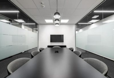 Minimalist conference room with a long black table and frosted glass walls.