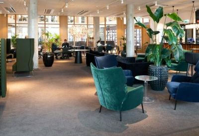 Spacious lounge area with teal and navy velvet armchairs and large indoor plants.