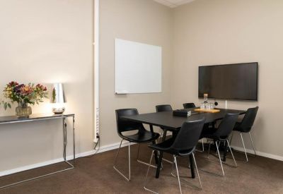 Small meeting room with a black table, chairs, a wall-mounted TV, and a whiteboard.