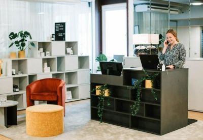 Stylish reception area with a dark desk, colorful seating, and open shelving.