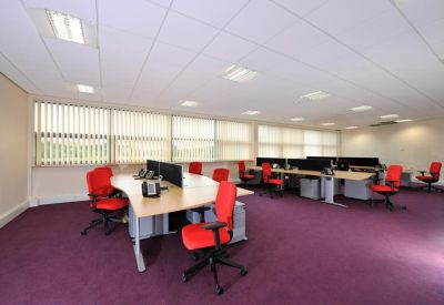 Open-plan office space with red ergonomic chairs and large desks with privacy dividers.
