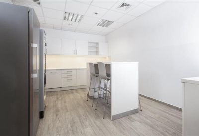 Communal kitchen area with white cabinetry and a high-top breakfast bar with stools.