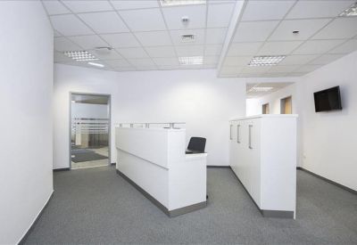 Reception area with sleek white desks and a wall-mounted television screen.