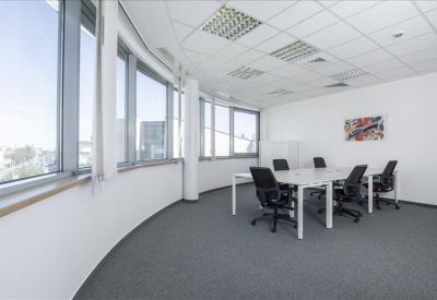 Spacious open-plan office with a curved window wall and multiple workstations.