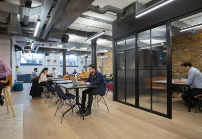 Spacious office area with cafe-style seating and glass-partitioned private meeting rooms.