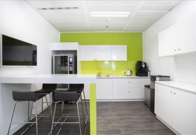 Modern kitchen and breakout area with a lime green feature wall and breakfast bar.