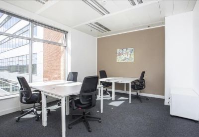 Bright corner office with white desks and a neutral feature wall.