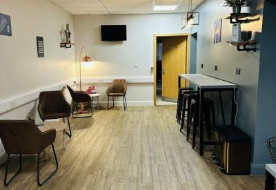 Communal breakout area featuring wood-style flooring and high-top seating.