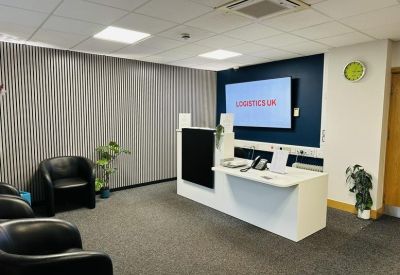 Modern reception area with a white desk and branded digital display on a blue wall.