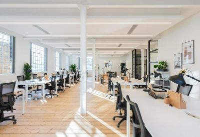Open-plan workspace with white desks, black ergonomic chairs, and large windows