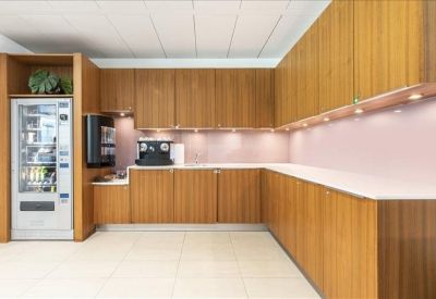 Modern kitchen and break area featuring warm wood cabinetry and a vending machine.