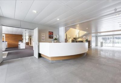 Bright reception area featuring a minimalist white curved desk and grey flooring.