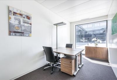 Bright private office with wooden desk and large window overlooking the courtyard.