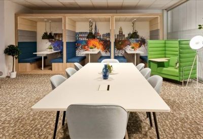 Spacious communal area with long white table and private acoustic booths with city murals.