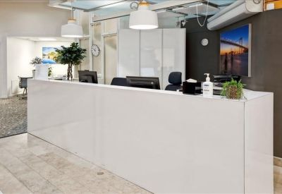 Sleek white reception desk with modern pendant lighting and indoor plants.