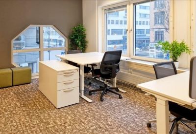 Bright office space featuring height-adjustable desks and ergonomic black chairs.