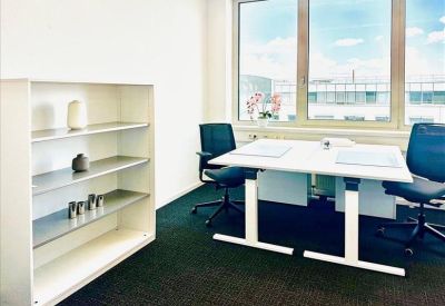 Bright private office featuring a white standing desk, ergonomic chairs, and a minimalist bookshelf.