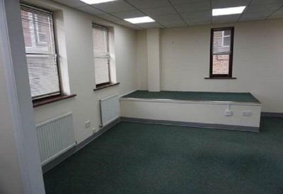 Bright office space with green carpeting, windows, and a raised floor platform.