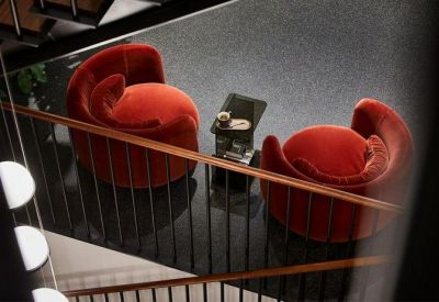 High-angle view of a breakout lounge with two plush orange armchairs and a marble side table.