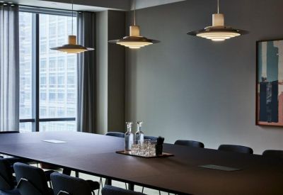 Sleek conference room with a long dark table, modern pendant lighting, and a large window.