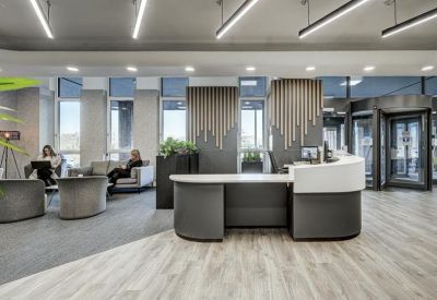 Modern reception desk with curved white and grey panels and a comfortable lounge seating area.