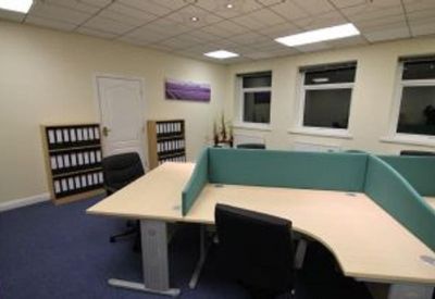 Spacious office workspace with curved desks, teal privacy screens, and blue carpeting.