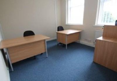 Small private office suite with two wooden desks and blue carpet.