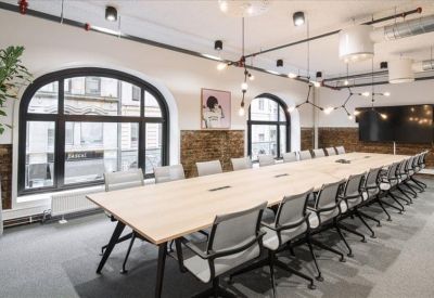Long boardroom table with grey chairs and modern pendant lighting.