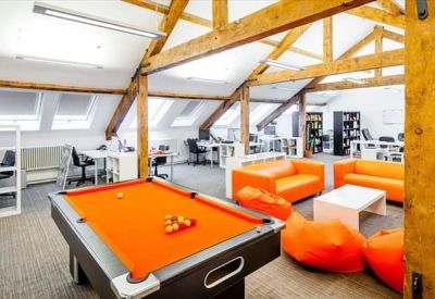 Vibrant breakout area with orange sofas, beanbags, a pool table, and exposed timber beams.