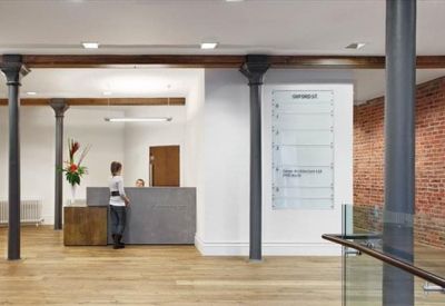 Modern reception lobby with a stone desk, brick feature wall, and industrial columns.