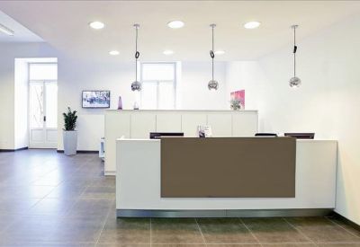 Professional reception area with a minimalist white desk and hanging pendant lights.