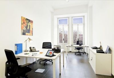 Bright, white office space with two desks and large windows.