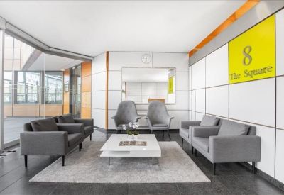 Lounge area with grey armchairs, sofas, and a yellow feature wall.
