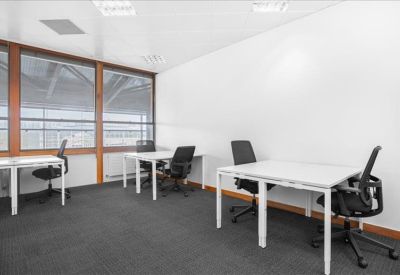 Bright private office featuring several white desks and black chairs.