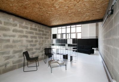 Sunlit lounge area with grey brick walls and a wooden ceiling.