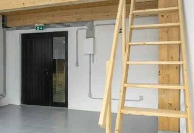 Bright workspace featuring white walls and a light wood loft ladder.