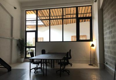 Minimalist meeting space with a black table and large warehouse windows.