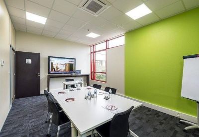 Bright meeting room with a lime green feature wall, conference table, and video conferencing screen.