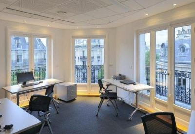 Light-filled workspace with white desks and multiple French doors opening to balconies.