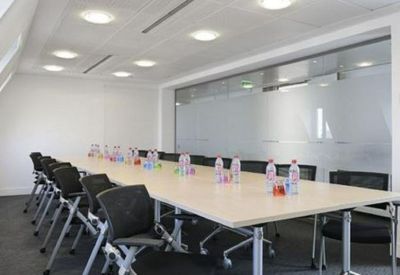 Spacious boardroom with a long white table and frosted glass walls.
