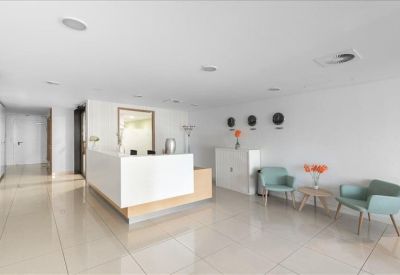 Bright reception lobby with white desk, blue armchairs, and world clocks on the wall.