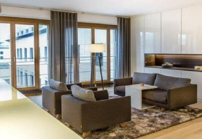 Comfortable lounge area with dark armchairs, a white side table, and large windows.