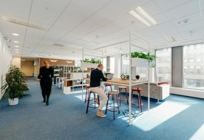 Spacious open coworking area with a high communal table and tall stools.