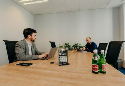 Meeting room with a long wooden table and people working on laptops.