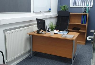 Private office suite with a wooden desk, bookshelf, and blue feature wall.