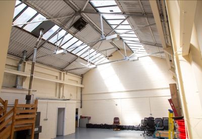 High-ceilinged warehouse space featuring a large skylight and white brick walls.