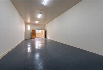 Long, empty industrial storage unit with grey floors and overhead lighting.